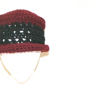May include: A crocheted hat with a burgundy and black color scheme. The hat has a wide brim and a textured design.