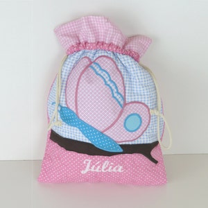 Può includere: Borsa a cordoncino rosa e blu con un design a farfalla e il nome "Julia" ricamato sul davanti.
