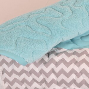 May include: A soft, blue baby blanket with a chevron pattern and a plush, textured top layer.