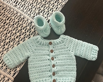 Suéter y patucos de bebé tejidos a crochet.