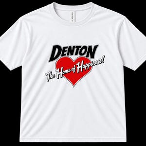 May include: A white short-sleeved t-shirt featuring a graphic on the chest. The graphic displays the word DENTON in bold black letters above a red heart. Below the heart, the text The Home of Happiness! is written in a white script font.