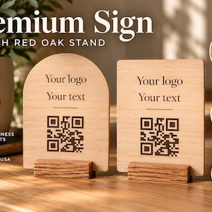 May include: Two light-colored wooden signs with red oak stands. One sign is arched and the other is rectangular. Both feature engraved text reading Your logo and Your text, along with a QR code. The signs are displayed on a wooden surface.