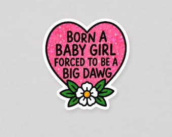 May include: A heart-shaped sticker with a pink glittery background featuring the black text BORN A BABY GIRL FORCED TO BE A BIG DAWG. At the bottom of the heart, there is a white flower with a yellow center and green leaves with black outlines.