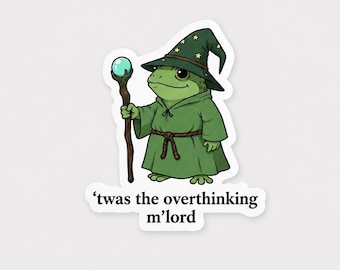 May include: A die-cut sticker featuring a green frog dressed as a wizard in a green robe and a pointed hat with yellow stars. The frog holds a brown wooden staff topped with a glowing light blue orb. Below the frog is the text 'twas the overthinking m'lord'.