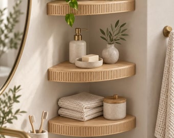 May include: Three light wood corner shelves with a vertical slatted front design mounted on a wall. The shelves hold a potted plant, a reed diffuser, a soap dispenser, a soap dish with soap, a small vase with greenery, folded towels, and a jar.