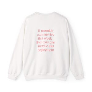 Könnte beinhalten: Ein weißes langärmeliges Sweatshirt mit Rundhalsausschnitt und rosafarbenem Text auf der Rückseite: if momtok can survive this week, then you can survive this deployment. Das Kleidungsstück hat einen gerippten Kragen, Bündchen und Saum.