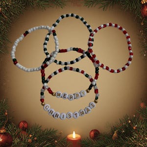 May include: A set of five circular beaded bracelets featuring a color palette of red, white, and dark green. Two of the bracelets include white letter beads with gold lettering that spell out the phrase MERRY CHRISTMAS in a stacked arrangement.