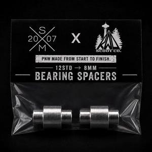May include: Two silver metal bearing spacers in a clear plastic bag with a black header card. The card features the text SM 2007, an X, the RWD Scoot Co logo, PNW MADE FROM START TO FINISH, and 12STD to 8MM BEARING SPACERS in white lettering.