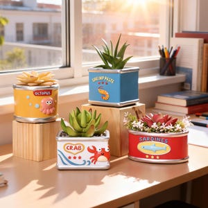 May include: Four decorative planters shaped like food cans, each featuring a succulent and a sea creature graphic. The yellow can says OCTOPUS, the blue says SHRIMP PASTE, the white says CRAB, and the red oval can says SARDINES with illustrations.