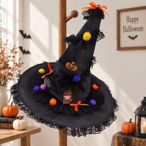 May include: A black pointed witch hat decorated with black lace trim, orange ribbons, and colorful pom-poms. The hat features a small patch of a smiling jack-o'-lantern and a cartoon witch character holding a pumpkin on the front cone section.