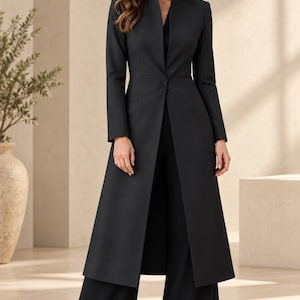 May include: A long-line black blazer featuring a high collar, long sleeves, and a single-button closure at the waist, paired with matching black wide-leg trousers. The blazer extends to the mid-calf, creating a structured and elongated silhouette.