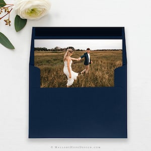 May include: A navy blue envelope with a white border and a photo of a couple holding hands in a field.