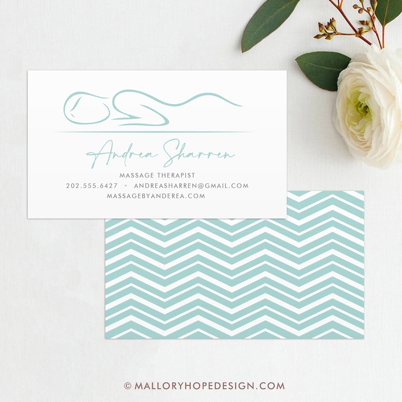 May include: A white business card with a light blue stylized illustration of a person lying down. The text "Andrea Sharren" is written in cursive script. The text "Massage Therapist" is written in all caps. The phone number 202.555.6427 and email address andreassharren@gmail.com are listed. The website address massagebyandrea.com is also listed. The business card is on top of a light blue and white chevron pattern.