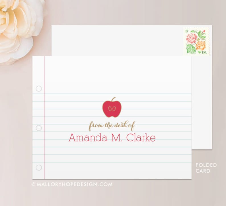 May include: A folded card with a red apple graphic and the text "from the desk of Amanda M. Clarke" on a white background with blue lines.