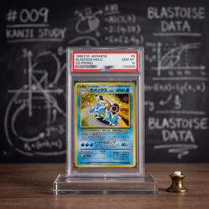 May include: A 1999 Japanese Blastoise holographic trading card encased in a clear protective PSA slab. The card features the blue Blastoise character, Japanese text, and a Gem Mint 10 grade label at the top. The slab is mounted on a clear stand.