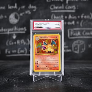 Könnte beinhalten: Eine holografische 1999 1st Edition Charizard Sammelkarte in einer transparenten PSA-Schutzhülle. Das Etikett zeigt 1999 POKEMON FRENCH DRACAUFEU - HOLO GEM MT 10. Die Karte zeigt eine Feuer-Drachen-Illustration mit 120 KP und roten Rändern.