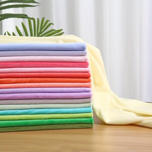 May include: A stack of folded fabric pieces in a variety of colors including pale yellow, light blue, lavender, pink, red, orange, peach, purple, grey, mint green, turquoise, lime green, bright green, and olive green with a soft texture.