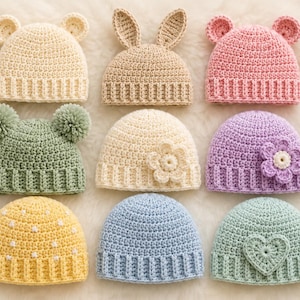 Op de afbeelding: Een collectie van negen gehaakte mutsen in diverse kleuren en ontwerpen, waaronder mutsen met berenoren, konijnenoren, pompons, bloemapplicaties, kleine witte stippen en een hartvormige patch, allemaal voorzien van een geribbelde boord.