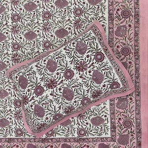 May include: A rectangular pillow and a matching bedspread featuring a white background with a repeating floral pattern in shades of dusty pink and muted green. The set includes a wide border with a pink edge and intricate botanical motifs.