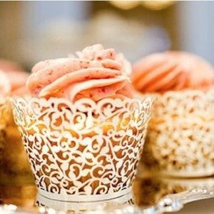 May include: Close-up of cupcakes with pink frosting and white lace paper liners. The cupcakes are arranged on a silver tray.