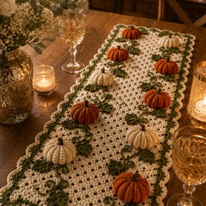 May include: A rectangular crochet table runner featuring an off-white openwork grid pattern with a scalloped dark green border. The runner is decorated with three-dimensional crocheted pumpkins in shades of orange and cream, accented by green vines.