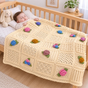 May include: A cream-colored crochet baby blanket featuring a grid of square panels with varied textured stitches and three-dimensional floral appliqués in shades of pink, blue, yellow, and purple, each accented with small green crocheted leaves.