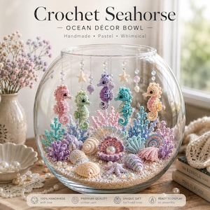 May include: A clear glass bowl filled with crochet seahorses and seashells. The seahorses in pink, green, purple, blue, and peach hang from the rim. The base contains crochet coral, various seashells, and a central shell holding a white pearl bead.