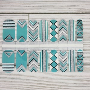 May include: Nail wraps with a turquoise, silver, black, and white geometric design. The nail art features chevron, triangle, and stripe patterns. The nail strips are arranged on a white backing, ready for application.