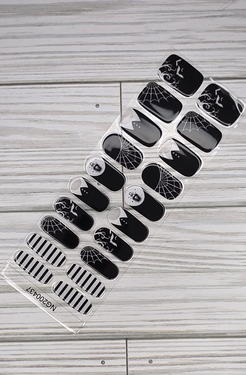 May include: A sheet of Halloween-themed nail art stickers. Designs include black and white stripes, spiderwebs, bats, and ghost images. The stickers are on a clear backing with the code NG200437.