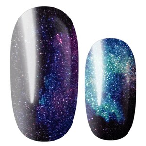 May include: Two oval-shaped nail polish bottles with a galaxy-inspired design. The polish on the left is a dark purple with silver glitter, while the polish on the right is a dark blue with green and silver glitter.