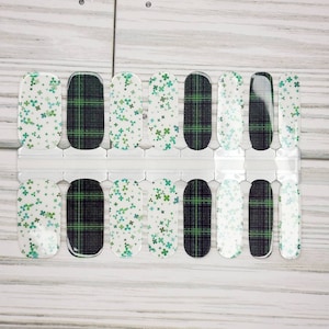 May include: A set of 10 nail wraps with two different designs. One design features a white background with green four-leaf clovers. The other design features a black and green plaid pattern.