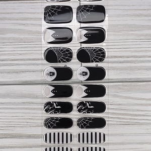 May include: Sheet of black and white nail wraps with Halloween-themed designs. The wraps feature bats, spiderwebs, and striped patterns. The product code "NG200437" is printed at the bottom.