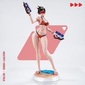 May include: A collectible figurine of a character with short dark hair, wearing a red bikini and a red eye mask. The figure holds two blue and black toy water pistols, one in each hand, and stands on a circular base with a sandy texture.