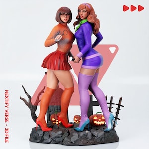May include: A 3D printed figurine set featuring two characters standing on a rocky graveyard base with carved pumpkins and a tombstone. One character wears an orange sweater and red skirt, the other a purple dress and light purple thigh-high boots.