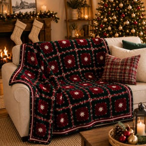 Può includere: Una coperta all'uncinetto con un motivo ripetuto di quadrati verde scuro e rosso intenso, ciascuno centrato con una stella bianca. La coperta è drappeggiata su un divano di colore chiaro, mostrando un design a griglia con bordi bianchi.