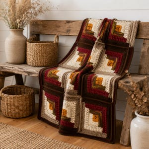May include: A crochet blanket featuring a geometric log cabin pattern composed of square blocks. The design incorporates a color palette of cream, dark brown, burgundy, mustard yellow, and olive green yarn, arranged in concentric rectangular layers.