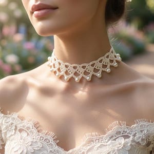 May include: A cream-colored crochet choker necklace featuring an intricate scalloped lace pattern and small, round white pearls attached along the bottom edge, worn around the neck above a matching cream-colored lace garment with long sleeves.