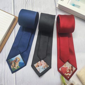 May include: Three satin neckties in navy blue, black, and deep red. Each tie features a custom rectangular photo print at the bottom tip. The navy tie displays a golden retriever, the black tie shows a couple, and the red tie depicts a family.