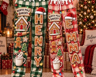 May include: Two pairs of pajama pants featuring a plaid pattern, one in green and white and one in red and white. Both feature gingerbread house graphics, North Pole Bakery text, gingerbread people, and names Henry and Emma.
