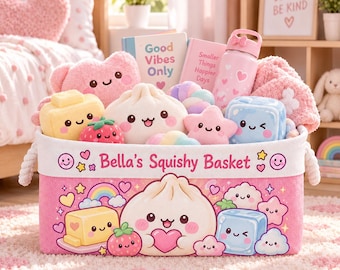 May include: A rectangular pink fabric storage basket labelled Bella's Squishy Basket, featuring cartoon graphics of a dumpling, strawberry, and ice cube. The basket is filled with various plush toys, including a dumpling, star, and cube, plus a pink water bottle.