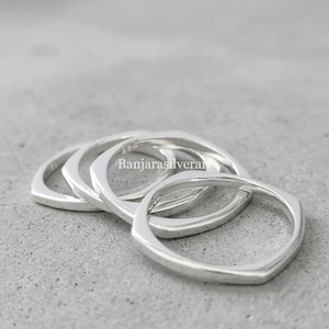Peut inclure: Un ensemble de trois bagues en argent poli avec un design de bande de forme carrée. Chaque bague présente une finition métallique lisse et une silhouette géométrique. Le texte Banjarasilverart est visible au centre des bagues.