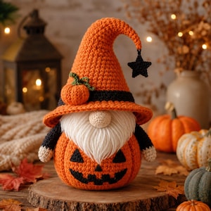 May include: A crochet gnome figurine featuring an orange pumpkin-shaped body with a black jack-o'-lantern face. The gnome wears a tall orange pointed hat with a black band, a small orange pumpkin accent, and a dangling black star charm.