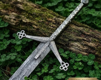 May include: A silver-toned claymore sword featuring a patterned Damascus steel blade and an intricate metal hilt with a cross-shaped guard ending in four-circle motifs. The handle has a textured, wrapped design and a rounded pommel at the end.
