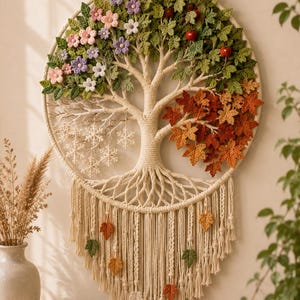 May include: A circular macrame wall hanging featuring a tree design representing four seasons. The tree has green leaves and flowers on the top left, red fruit on the top right, white snowflakes on the bottom left, and orange autumn leaves on the bottom right.