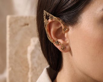 May include: An ear cuff crafted from antique gold-toned metal, featuring an intricate design of climbing vines, delicate leaves, and small rose blossoms. The piece wraps around the outer edge of the ear, extending from the top to the lobe.