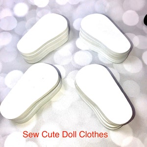 May include: Four stacks of white, oval-shaped doll clothes patterns are arranged on a light, bokeh background. The text "Sew Cute Doll Clothes" is printed in red at the bottom of the image.