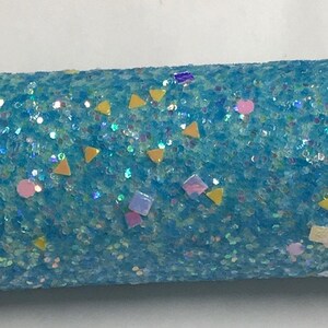 May include: Close-up of a turquoise glittered object with iridescent sparkles. The object is decorated with small, colorful shapes, including yellow triangles, pink circles, and purple squares. The background is plain white.