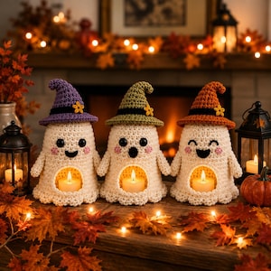 Può includere: Tre statuette di fantasmi all'uncinetto in filato color crema, ognuna con un cappello a punta viola, verde o arancione con un piccolo fiore. Ogni fantasma ha occhi neri, bocca ricamata, guance rosa e un centro cavo con una candela accesa.
