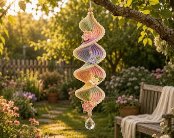 May include: A spiral-shaped crochet hanging ornament featuring a gradient of pastel colors including pink, yellow, and green. The piece is decorated with small crocheted flowers and leaves, finished with a clear faceted crystal bead at the bottom.