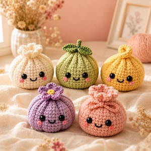 Puede incluir: Cinco pequeños juguetes de peluche tejidos a ganchillo, redondos, con caras sonrientes, ojos de cuentas negras y mejillas rosadas. Los juguetes son crema, verde claro con una hoja, amarillo, morado con una flor y rosa claro, con un nudo.